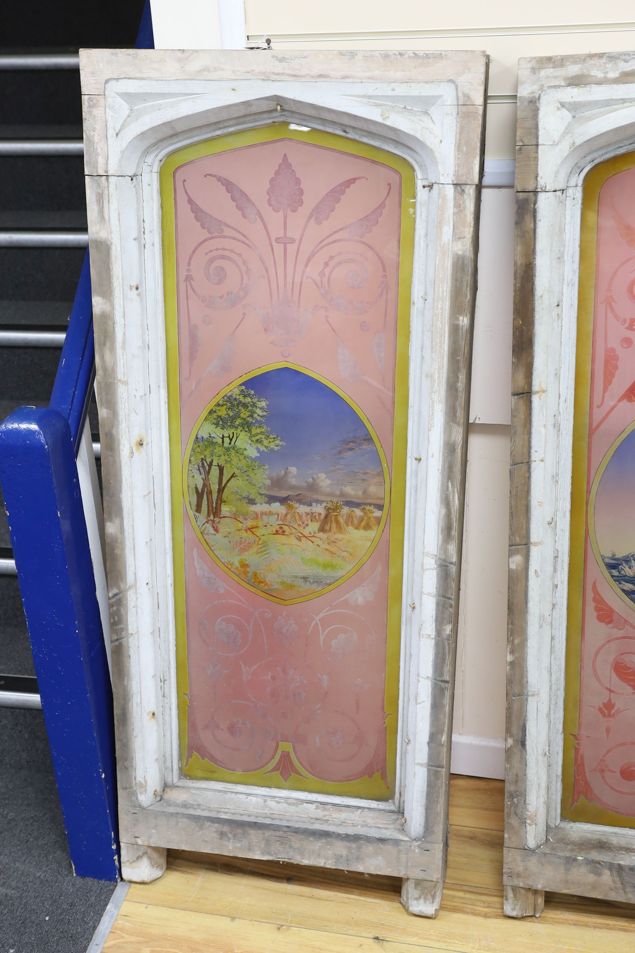 A pair of early 20th century Gothic style painted glass windows depicting an ice breaker and a corn field, W 62cm, D 17cm, H 151 cm